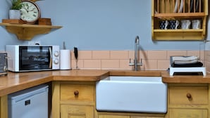 A kitchen with a Breville microwave, a sink, wooden cabinets, and a clock on the wall. - 19th Century Cottage Near Brixham Harbour (Brixham)