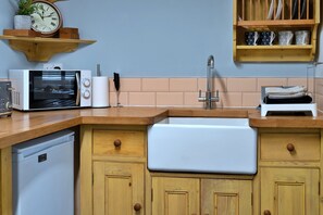 A kitchen with a Breville microwave, a sink, wooden cabinets, and a clock on the wall. - 19th Century Cottage Near Brixham Harbour (Brixham)