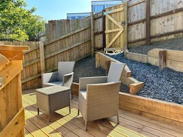 An outdoor deck with wicker furniture and a wooden fence.