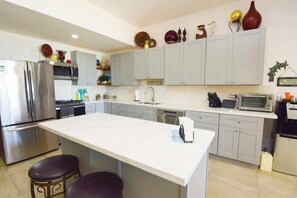 Une cuisine moderne dotée d’un îlot central, d’appareils électroménagers en acier inoxydable et de meubles de cuisine de couleur claire.