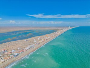 Eine Luftaufnahme einer Küstenregion mit Strand, Gebäuden und blauem Himmel.