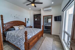 A bedroom with a wooden bed, ceiling fan, and a TV. - Casa Mareas | Luxury Beachfront Estate | Spa | 6BR (Playa Encanto)