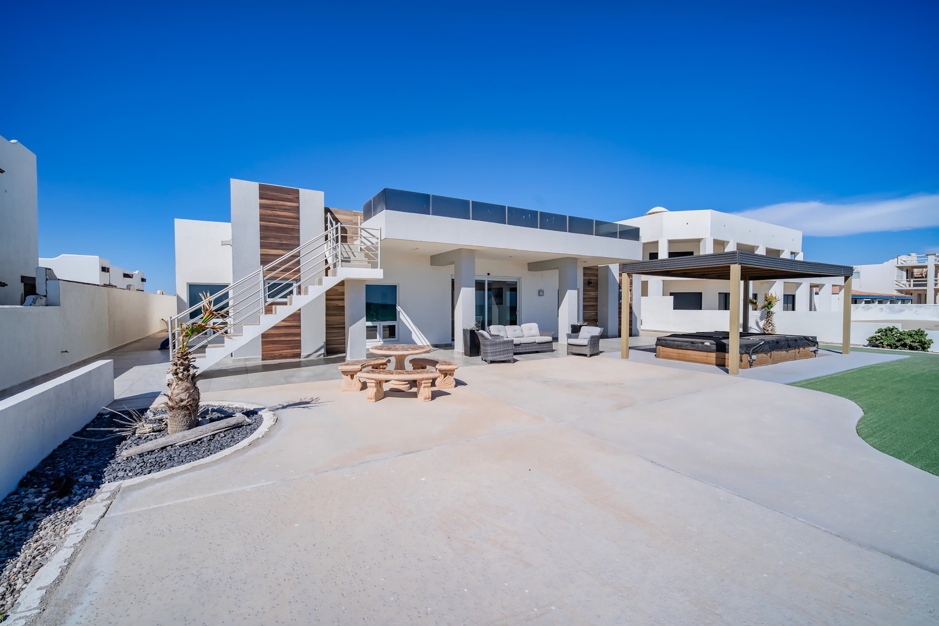 Un edificio residencial moderno con un porche cubierto, asientos exteriores y una escalera que conduce a los niveles superiores.
