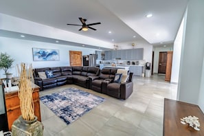 A modern living room with a sectional sofa, a dining area, and a kitchen. - Casa Mareas | Luxury Beachfront Estate | Spa | 6BR (Playa Encanto)