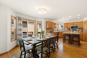 A modern kitchen with wooden cabinets, a central island, and a dining area with a table set for four.