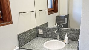 A bathroom with a white sink, a mirror, a towel rack, and a bottle of hand soap. - Arvenstudio by Interhome (La Punt-Chamues-ch)
