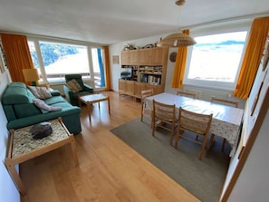 Ett kompakt bostadsutrymme med en soffa, ett matbord och ett litet kök.
