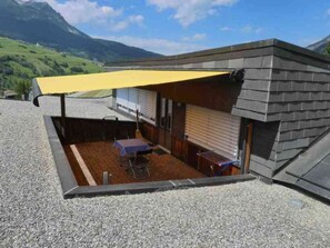 Ein kleines Gebäude mit einer überdachten Terrasse, einem Tisch und Stühlen.