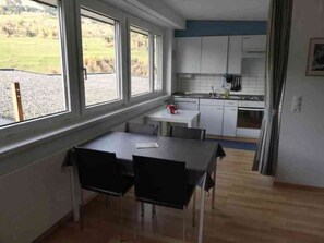 A kitchen with a dining area, large windows, and a view of the outdoors. - Tgesa Sunnmatt Nr 46 Appartement/Fewo, Dusche, WC, 1 Schlafraum by Interhome (Savognin)