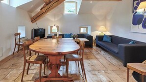 A spacious loft with a high ceiling, exposed wooden beams, a large round wooden dining table, and a cozy seating area with a sofa and armchairs. - Palazzo Appartement/Fewo, Dusche, WC, 3 Schlafräume by Interhome (Bivio)