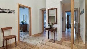A hallway with wooden flooring, a wooden chair, a small table with a vase, and a mirror on the wall. - Palazzo Appartement/Fewo, Dusche, WC, 3 Schlafräume by Interhome (Bivio)