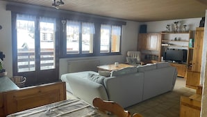 Uma sala de estar aconchegante com um sofá, uma mesa de jantar de madeira e uma televisão.