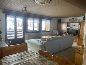 Ein gemütliches Wohnzimmer mit einer Couch, einem Holzesstisch und einem Fernseher.