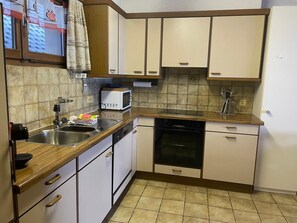 Eine kleine Küche mit Spüle, Mikrowelle, Backofen und einer Arbeitsplatte.