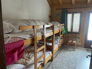 A bunk bed room with a window, a door, and a small chair. - Ferienhaus Somareiva Appartement/Fewo, Dusche oder Bad, WC, 2 Schlafräume by Interhome (Savognin)