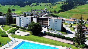 Un hôtel doté d’une piscine, entouré de collines verdoyantes et de montagnes.