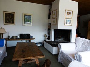 A living room with a fireplace, a sofa, a wooden table, and a bookshelf. - Penthouse Tgesa Tgampi T33 Appartement/Fewo, Bad, WC, 2 Schlafräume by Interhome (Savognin)