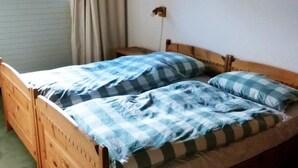 Un lit simple avec un cadre en bois, une couvre-lit à carreaux et un seul oreiller.