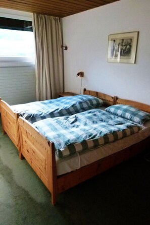 Ein Einzelbett mit Holzrahmen, einer karierten Tagesdecke und einem Kopfkissen.