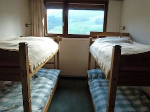 A room with two bunk beds, a window with a view of the outdoors, and a radiator between the beds. - Penthouse Tgesa Tgampi T33 Appartement/Fewo, Bad, WC, 2 Schlafräume by Interhome (Savognin)