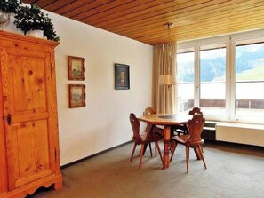 Ein Essbereich mit einem Holztisch, Stühlen, einer Kommode und gerahmten Bildern an der Wand.