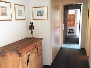 A hallway with a wooden dresser, framed pictures on the wall, and a door leading to another room. - Penthouse Tgesa Tgampi T33 Appartement/Fewo, Bad, WC, 2 Schlafräume by Interhome (Savognin)