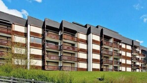 Un immeuble résidentiel à plusieurs étages, doté de balcons, d’un toit plat et surplombant un ciel dégagé.