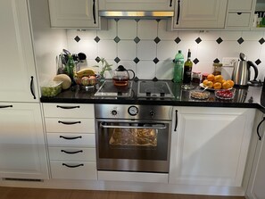 Una cocina moderna con armarios blancos, un horno de acero inoxidable y una encimera negra.