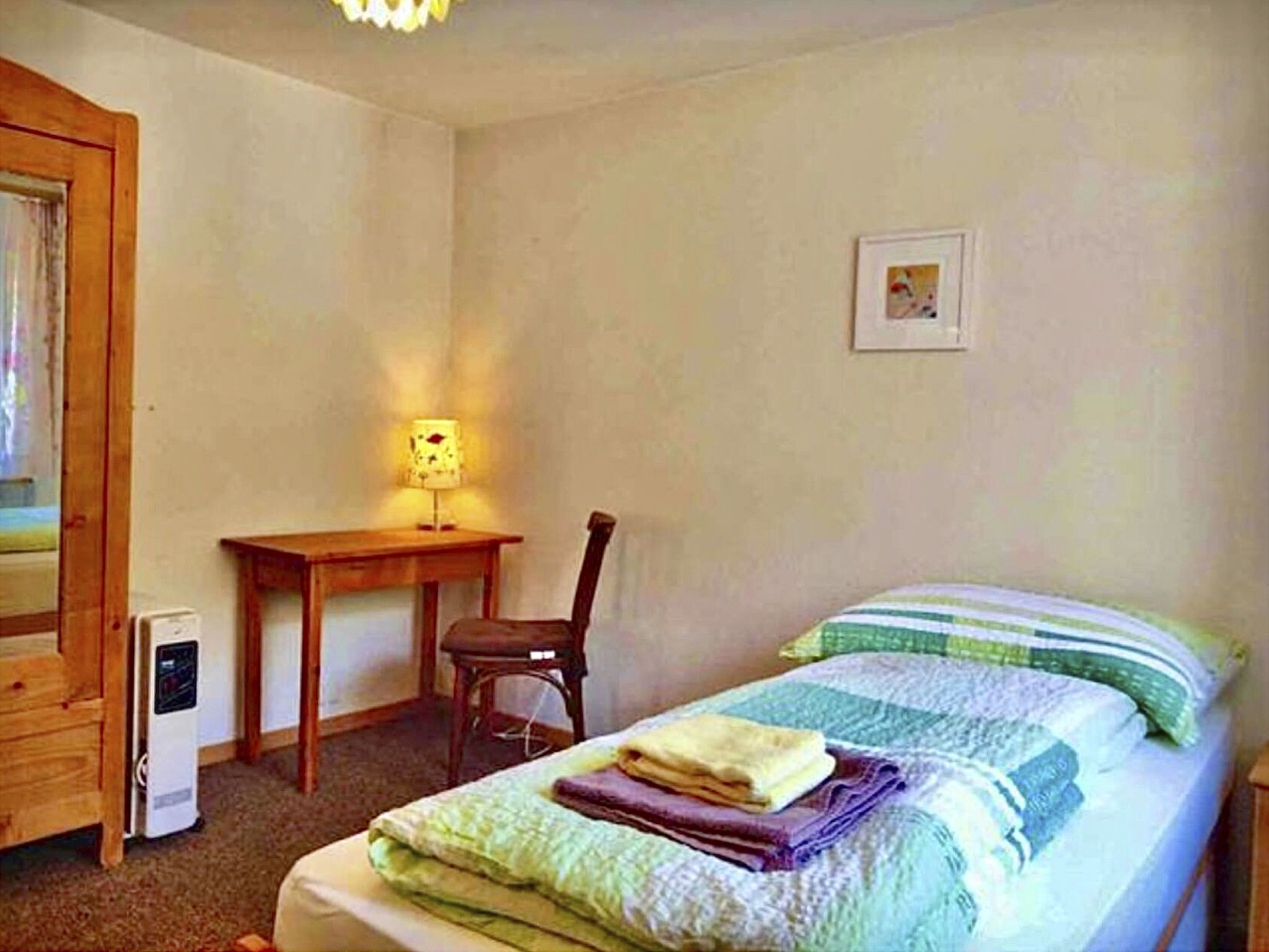 Una camera da letto con un letto, una scrivania, una sedia e un quadro appeso al muro.