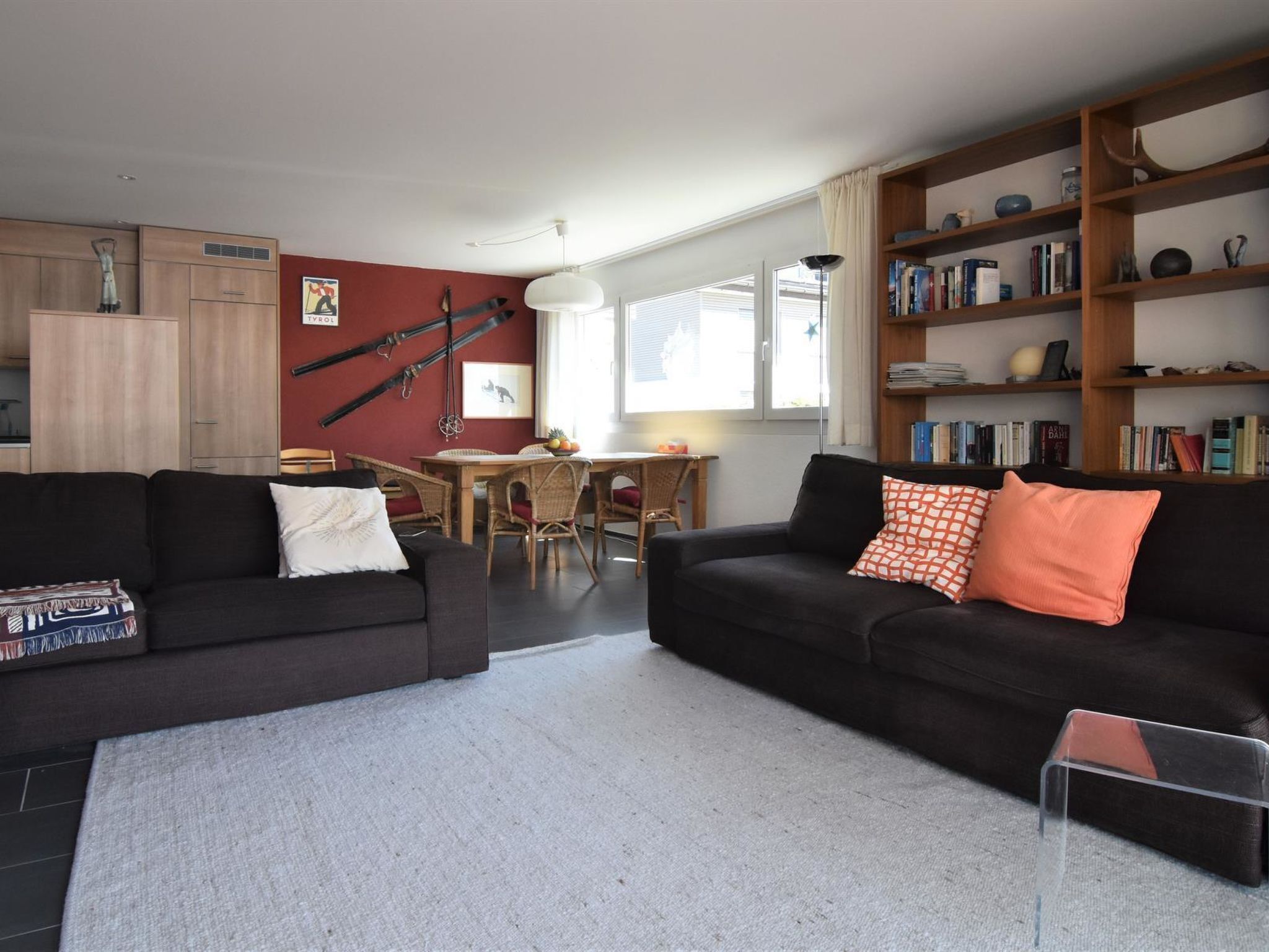 A living room with two sofas, a dining table, and a bookshelf.
