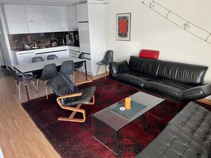 A modern living space with a dining area, a black leather sofa, and a red rug. - Som Barnagn 7 Appartement/Fewo, Bad, WC, 3 Schlafräume by Interhome (Savognin)