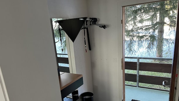 Pieni huone, jossa on ovi, joka johtaa parvekkeelle, roskakori ja pöytä.