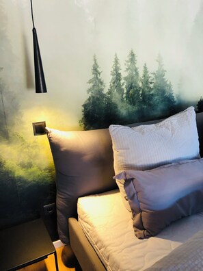 A bedroom with a bed, pillows, a bedside table, and a wall-mounted lamp. - Panoramic Apartment in the Black Forest, Prime Location, Terrace, Garden, Near Baden-Baden (Bühlertal)