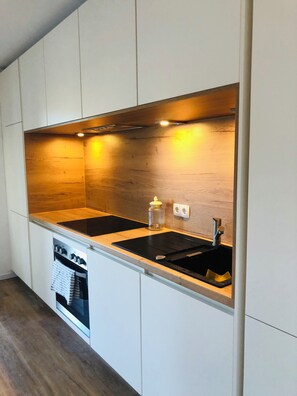 A modern kitchen with two black countertops, a stainless steel sink, and wooden cabinetry. - Panoramic Apartment in the Black Forest, Prime Location, Terrace, Garden, Near Baden-Baden (Bühlertal)