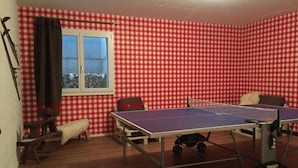 Una habitación con mesa de ping pong, ventana y un diseño de pared a cuadros.