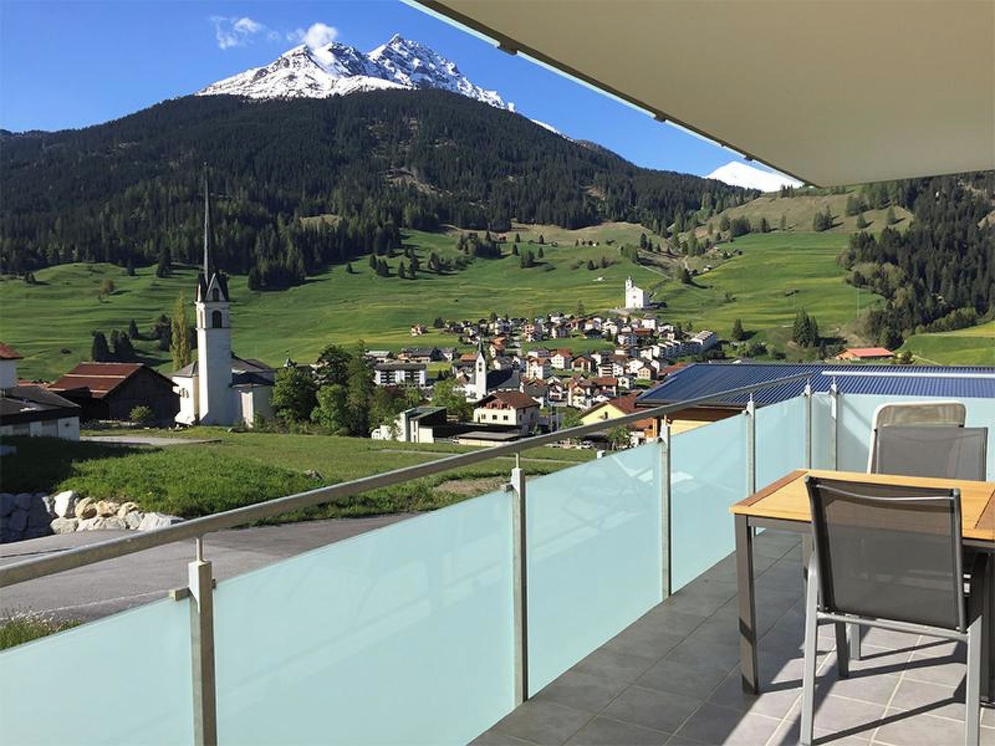 Un balcon avec vue sur une montagne, une église et un village.