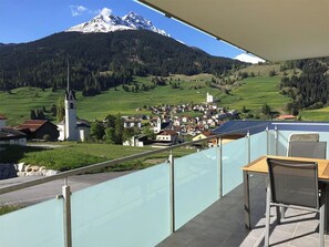 Ein Balkon mit Blick auf einen Berg, eine Kirche und ein Dorf.