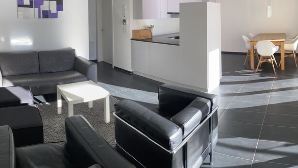 Una sala moderna con sofá, mesa de centro y comedor con mesa y sillas.