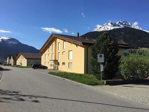 Eine Wohnstraße mit einem gelben Gebäude, einem parkenden Auto und einem Verbotsschild.