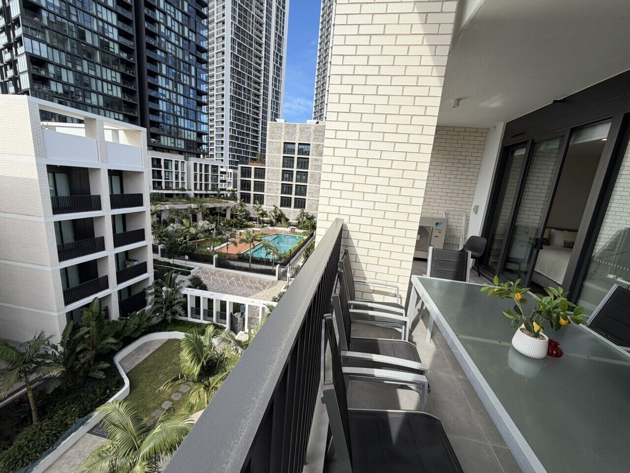 A residential building with a balcony overlooking a swimming pool and lush greenery.