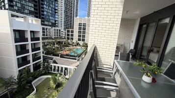 A residential building with a balcony overlooking a swimming pool and lush greenery.