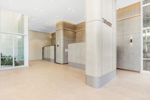 A modern reception area with a glass facade, a central pillar labeled 'POWER2', and a tiled floor. - Spacious Pool Retreat with Gym Pool BBQ Rooftop (Lidcombe)