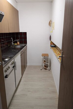A compact kitchen with a stove, sink, and wooden cabinets. - Curtinfess Rezzonico Appartement/Fewo, Bad, WC, 1 Schlafraum by Interhome (Bivio)