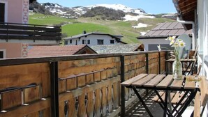 A balcony with a wooden railing, a table with a vase of flowers, and a view of snow-capped mountains in the background. - Casa Fasciati Appartement/Fewo, Bad, WC, 4 oder mehr Schlafräume by Interhome (Bivio)