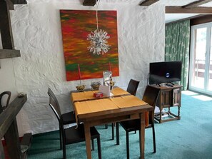 A dining area with a table, chairs, a television, and a painting on the wall. - Haus Viols 54 Appartement/Fewo, Bad, WC, 2 Schlafräume by Interhome (Savognin)