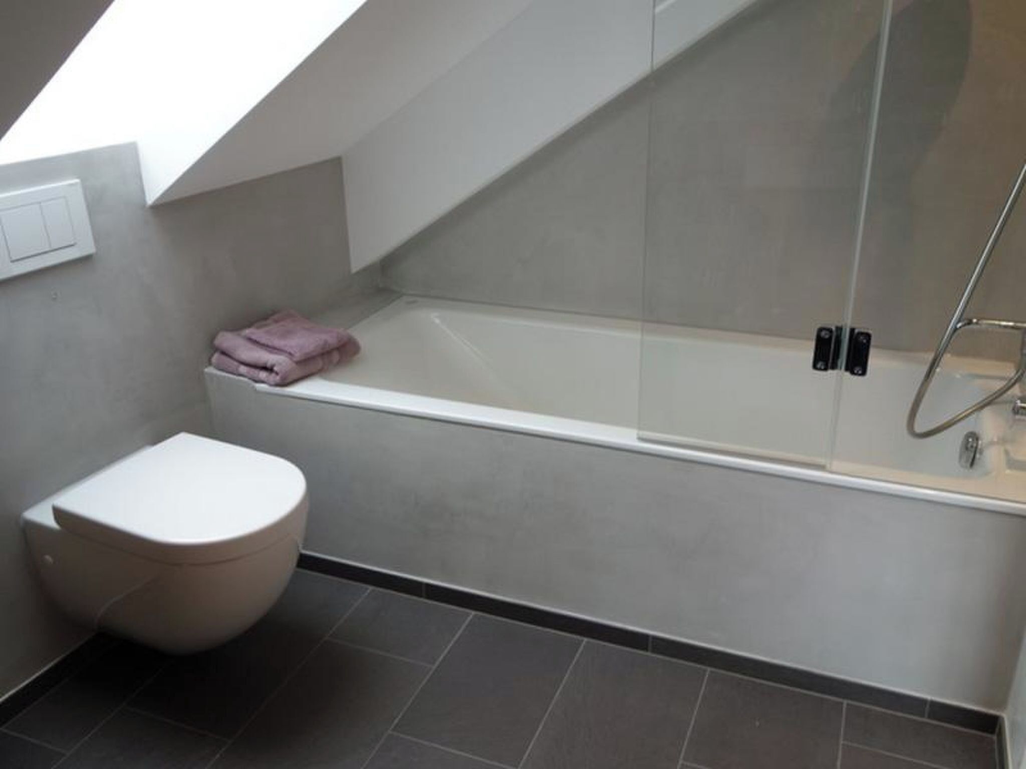 Een moderne badkamer met toilet, een bad en een douchehoek.