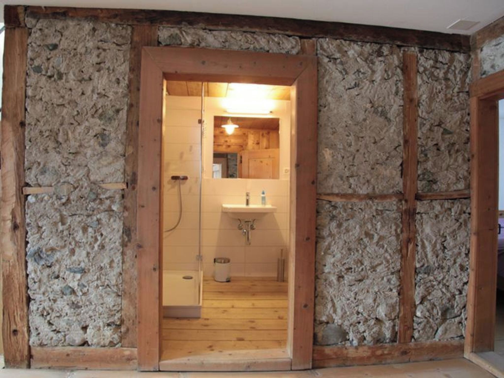 A bathroom with a wooden door, a sink, and a mirror.