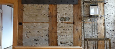 A rustic interior with a wooden bench, stone wall, and metal furniture.