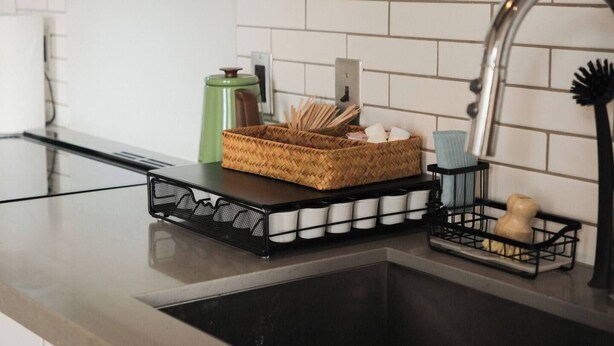 A kitchen counter with a woven basket, a metal rack with cups, and a soap dish. - Penthouse Loft, Central Downtown Dallas, Pool+Gym+Office, City Views (Dallas)
