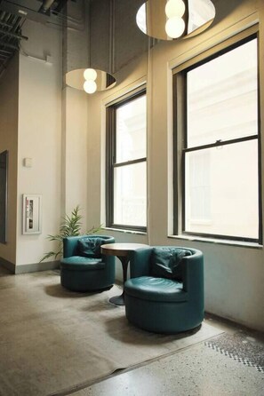 A modern interior with two round teal chairs, a small table, and large windows allowing natural light. - Penthouse Loft, Central Downtown Dallas, Pool+Gym+Office, City Views (Dallas)